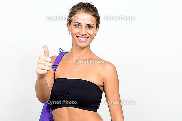 Studio shot of young beautiful woman with curly hair ready for gym against white background [IBR124309064]