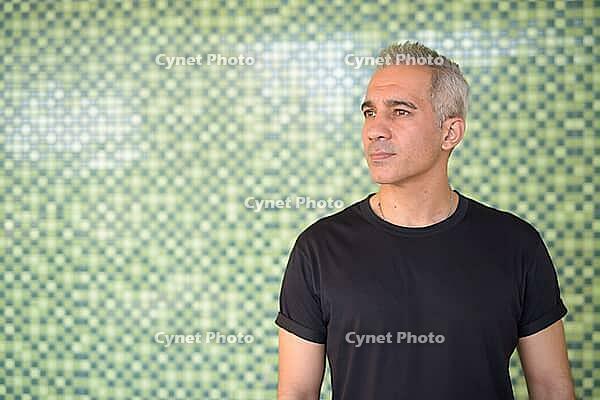 Portrait of handsome Persian man with gray hair against green wall outdoors [IBR124309084]