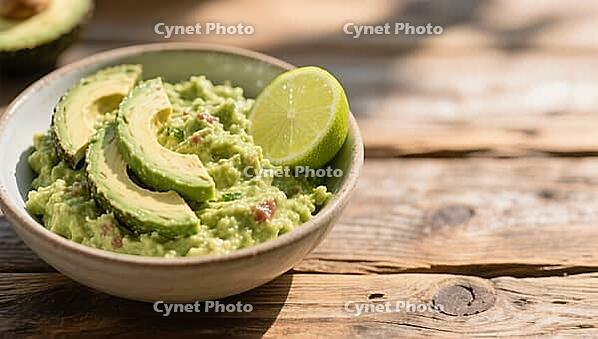 Bowl of guacamole decorated with avocado and lime slice on a wooden table surface, delicious dip, perfect as a side dish for meals and parties, AI generates, AI generated [IBR124458873]
