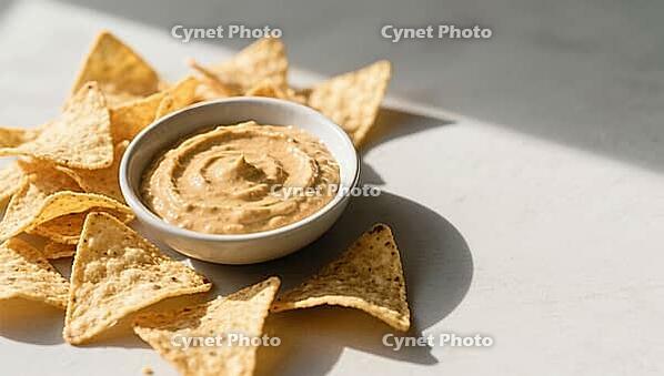 Tortilla chips arranged around a bowl of creamy dip on a table with light-shadow contrast, delicious dip, perfect as a side dish for meals and parties, AI generates, AI generated [IBR124458890]