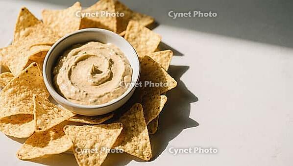 Yellowish dip in a bowl surrounded by tortilla chips in sunlight, delicious dip, perfect as a side dish for meals and parties, AI generates, AI generated [IBR124458902]