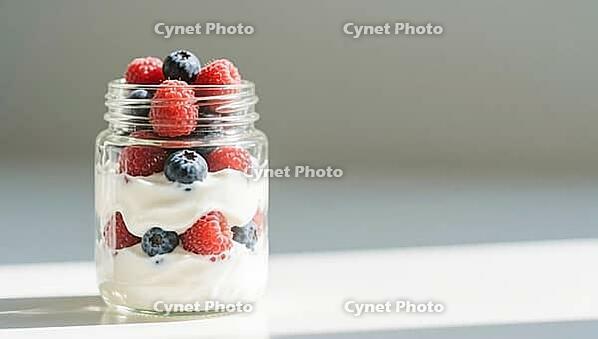 A glass with yogurt and berries, simple design, strong natural light, delicious dessert, beautifully presented, AI generated [IBR124458903]