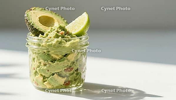 Guacamole in a glass container, decorated with fresh avocado and lime wedges in bright light, delicious dip, perfect as a side dish for meals and parties, AI generates, AI generated [IBR124458911]