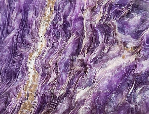 Macro shot of a natural mineral stone background made of tumbled charoite gemstone [IBR124458922]