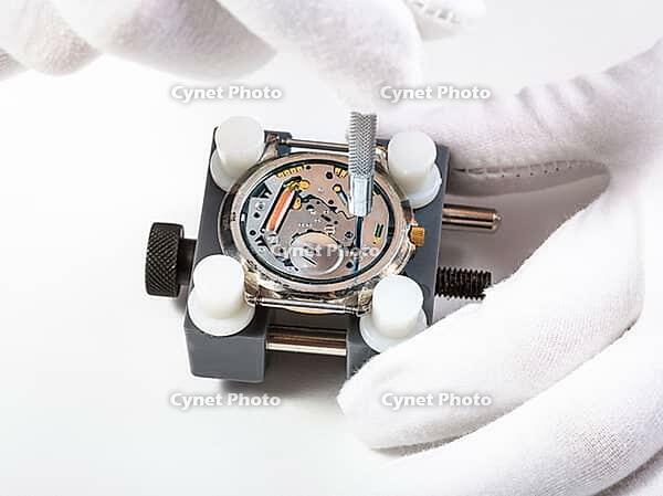 Watchmaker workshop close-up repair of quartz watches with screwdriver on white background [IBR124458925]