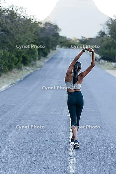 Full length slim female walking on an abandoned road and warming up her body before an outdoor workout [IBR124491541]