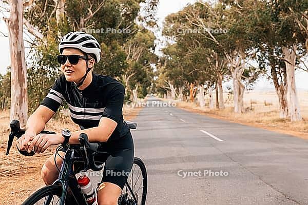 Woman cyclist sitting on her bike resting during outdoors ride [IBR124491542]