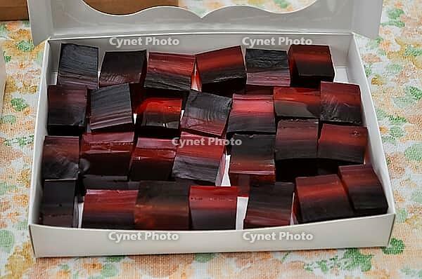 A box filled with colorful, layered square candies, showcasing a unique blend of red and black hues, perfect for dessert [IBR124491561]