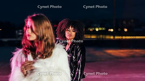 One young girl stands behind the other and looking down [IBR124491586]