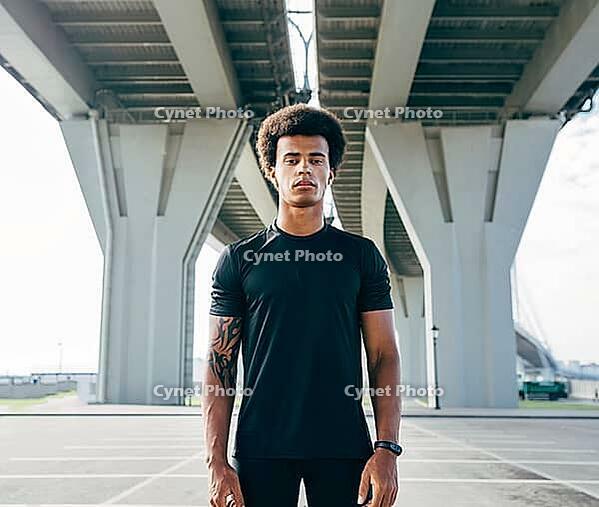 Young man in black sports clothes standing under a highway [IBR124491593]