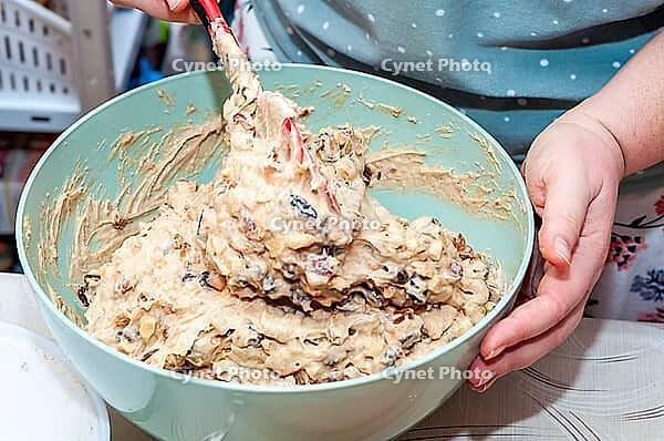 A person is mixing cake batter in a bowl with a spatula, preparing for baking. Various ingredients are visible within the mixture, ready to be baked [IBR124491603]