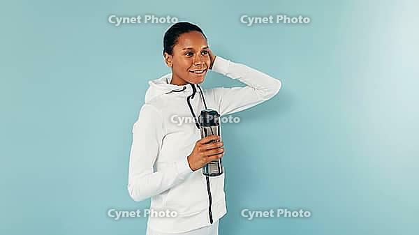 Young smiling woman posing in studio with a bottle of water [IBR124491609]