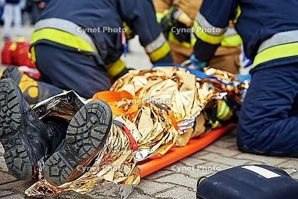 Rescuers provide first aid to the victim during a car accident. Person injured in the accident is lying on the road [IBR124497428]