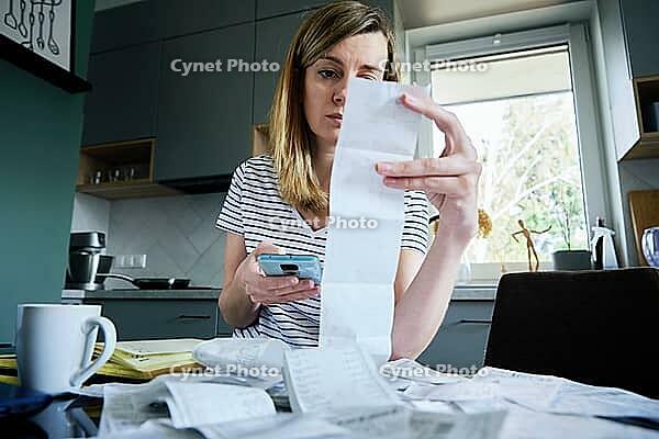 Woman looking at paper bill and counting expenses, Planning budget and home finance management [IBR124497430]