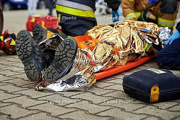 Rescuers provide first aid to the victim during a car accident. Person injured in the accident is lying on the road [IBR124497437]