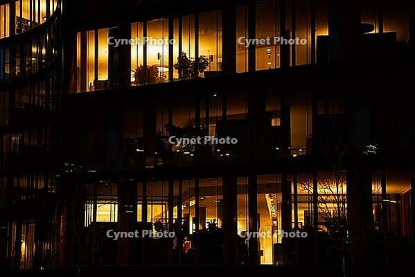 Office building exterior with glowing lights in windows at night city. Vienna city downtown district with skyscraper facades. Night city panorama. Working late at corporation [IBR124497443]