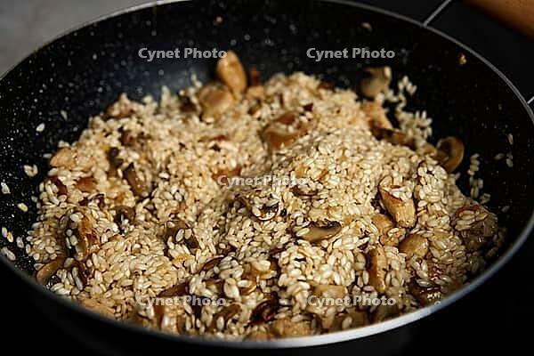 Process of cooking risotto. Arborio rice in frying pan at home kitchen. Italian cuisine dish [IBR124497477]