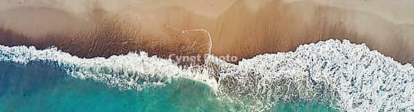 Sand beach with sea waves, top view. Summer vacation and travel concept. Beautiful coastline with blue sea and sand beach, aerial view [IBR124497482]