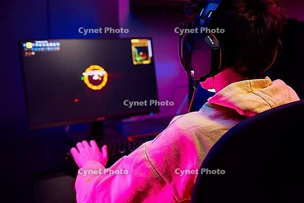 Teenager boy play computer video game in dark room, use neon colored rgb mechanical keyboard, workplace for cybersport gaming, children gaming addiction [IBR124497484]
