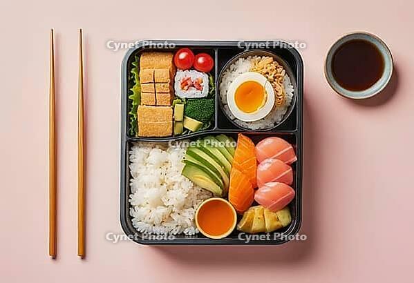 A top-down view of a meticulously arranged bento box showcasing a variety of Japanese delicacies including sushi rolls, steamed rice, fresh salmon slices, and a perfectly cooked egg, AI generated [IBR124550805]