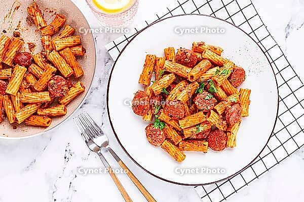 Rigatoni pasta with spicy sausage, and rich tomato sauce served, on a white plate, homemade [IBR124552176]