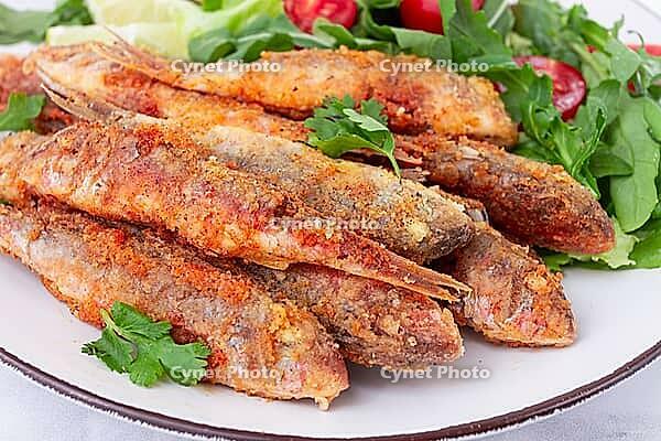 Fried crispy mullet fish, with fresh salad, on a plate with lime, no people [IBR124552180]