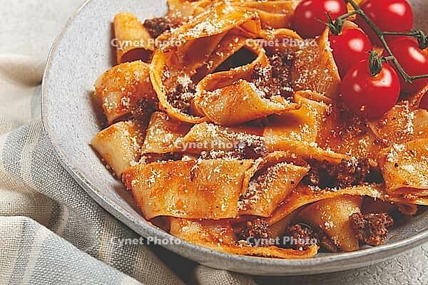 Pappardelle pasta with bolognese sauce, topped with parmesan cheese and cherry branch, homemade, no people [IBR124552192]