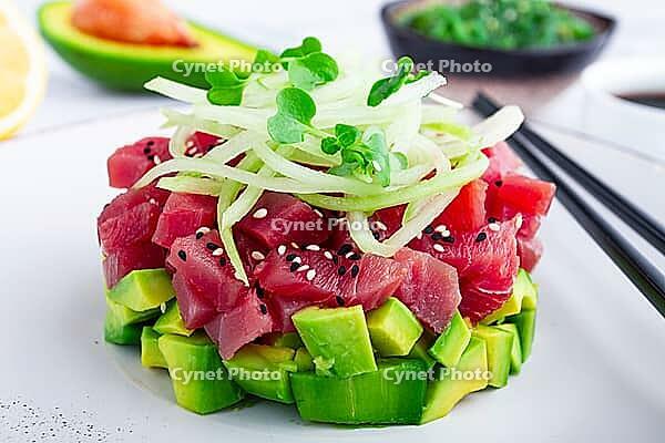 Fresh tuna tartare with avocado served on a marble table with soy sauce and seaweed salad [IBR124552193]