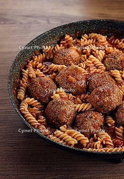 Minced meat meatballs, in tomato sauce, with fusilli pasta, in a cast-iron pan, homemade, no people [IBR124552194]