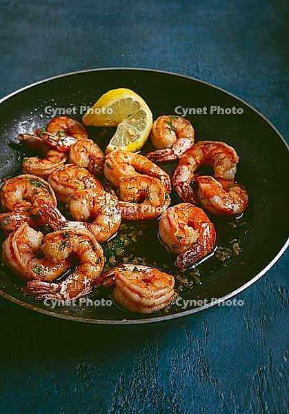 Fried tiger prawns, jumbo, in garlic sauce, in butter, with herbs, in a frying pan, homemade, no people [IBR124552221]