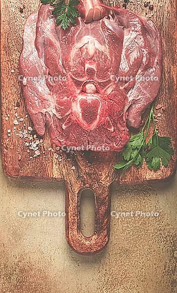 Raw steak, veal neck on the bone, fresh meat, on a cutting board, with spices, top view, without people [IBR124552236]