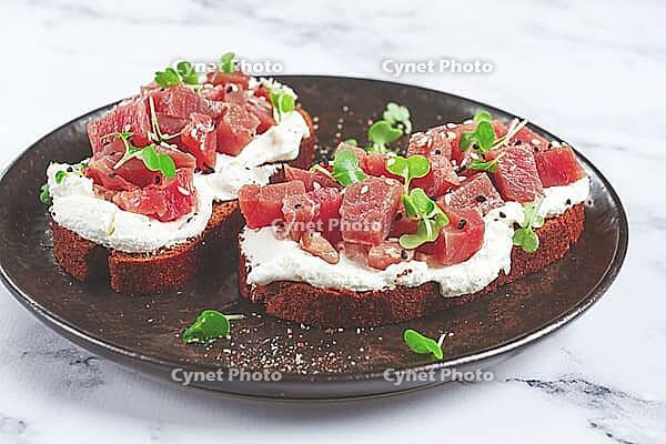 Sandwiches, rye bread with cream cheese, sliced tuna fillet with herbs, breakfast on a black plate, homemade [IBR124552241]