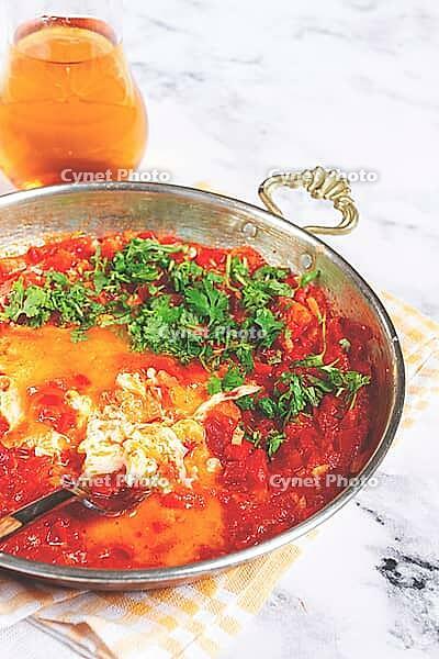 Traditional Turkish dish, scrambled eggs with tomatoes, Menemen, with herbs, in a frying pan, close-up, no people [IBR124552254]