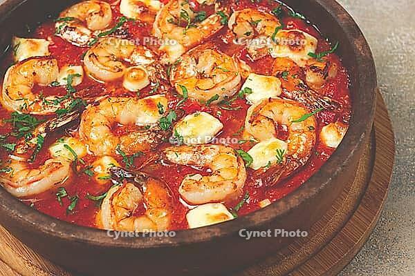 Saganaki with shrimp, in a clay pan, Greek dish, shrimp in tomato sauce, feta cheese, homemade, no people [IBR124552259]