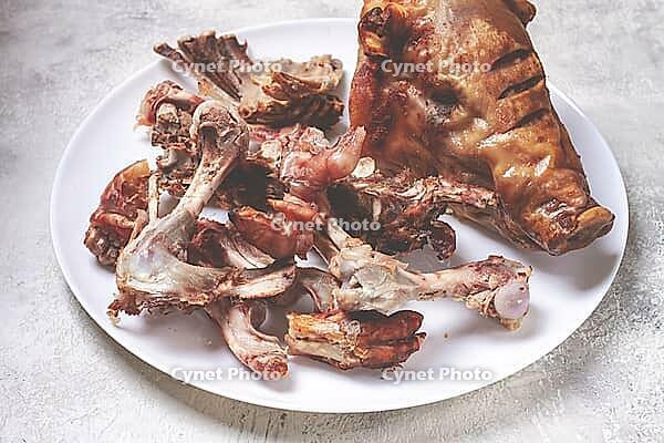 Roast pork head, with remnants of bones and meat, on a white platter, no people, close-up [IBR124552265]