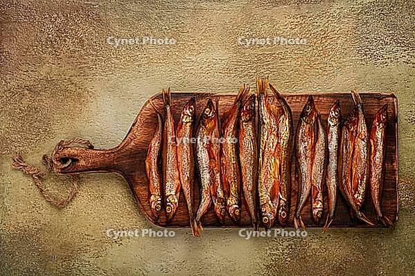Cold smoked capelin, on a wooden chopping board, no people [IBR124585334]