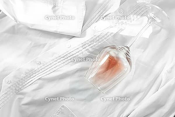 Glass, with pink wine, spilled on a white shirt, close-up, selective focus, no people, concept, top view [IBR124585343]