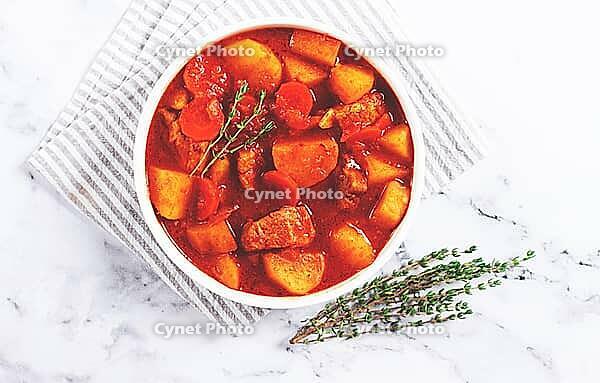 Meat goulash with potatoes and carrots, sweet peppers, in a saucepan, top view, traditional Hungarian soup, homemade, no people [IBR124585345]