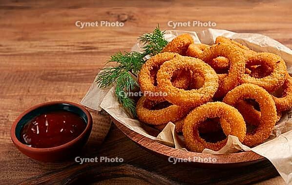 Deep fried onion rings, appetizer, with tomato sauce, on a wooden table, no people, favorite dish [IBR124585349]
