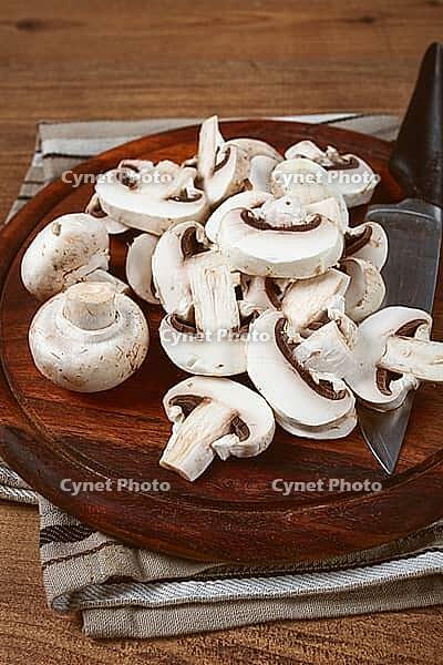 Fresh mushrooms, chopped, in a wooden bowl, whole, top view, no people [IBR124585361]