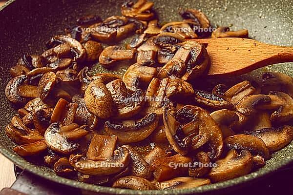 Fried mushrooms in a frying pan, with a wooden fork, homemade, no people [IBR124585365]