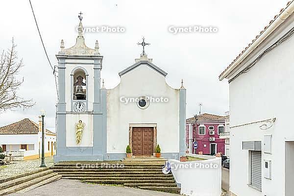 View of Igreja Paroquial de São Marcos da Serra, the parish church of São Marcos da Serra village in the Algarve interior of Portugal, surrounded by traditional white houses, rolling hills, and rural countryside [IBR124586579]