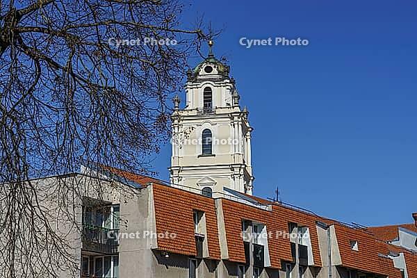 Historic church tower above modern residential buildings with branched trees, Vilnius, Lithuania, Baltic States [IBR124586580]