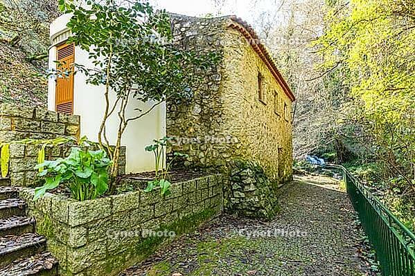 Traditional stone mill surrounded by lush forest in Barranco dos Pisões Park, Monchique, Algarve, Portugal, showcasing rural architecture and natural scenery [IBR124586595]