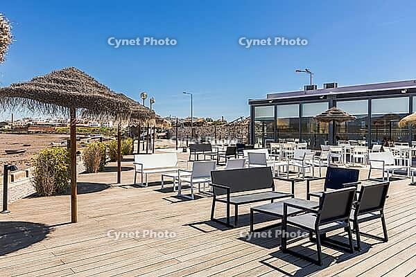 Outdoor terrace with white tables and chairs under thatched umbrellas overlooking riverside landscape near Agua Hotels Riverside in Lagoa, Algarve, Portugal [IBR124586601]