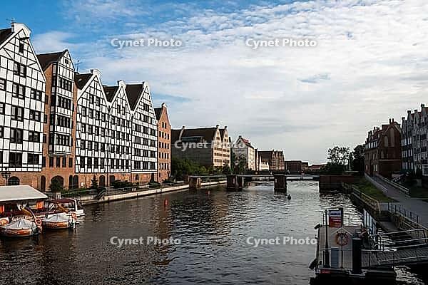 Gdansk, Poland - June 28, 2015 - Historic architecture along riverside with bridges and boats under blue sky [IBR124626845]