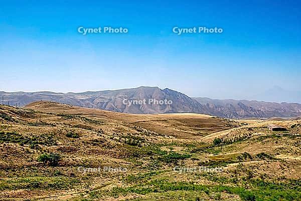 Expansive mountainous landscape with rolling hills under clear blue sky [IBR124626847]