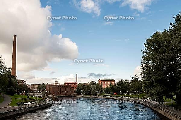 Tampere, Finland - August 29, 2014 - Tranquil river in urban park setting with industrial skyline and blue sky [IBR124626850]