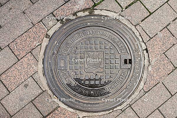 Helsinki, Finland - August 28, 2014 - Helsinki manhole cover on cobblestone street [IBR124626857]