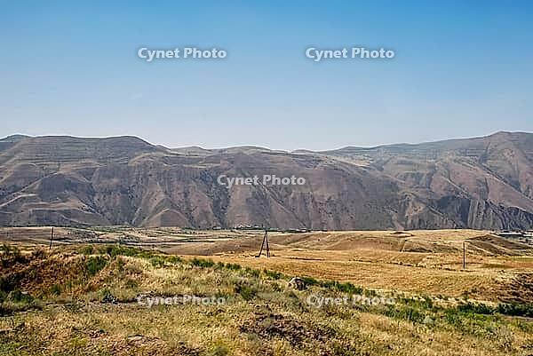 Panoramic view of arid mountain range and grasslands under clear blue sky [IBR124626863]